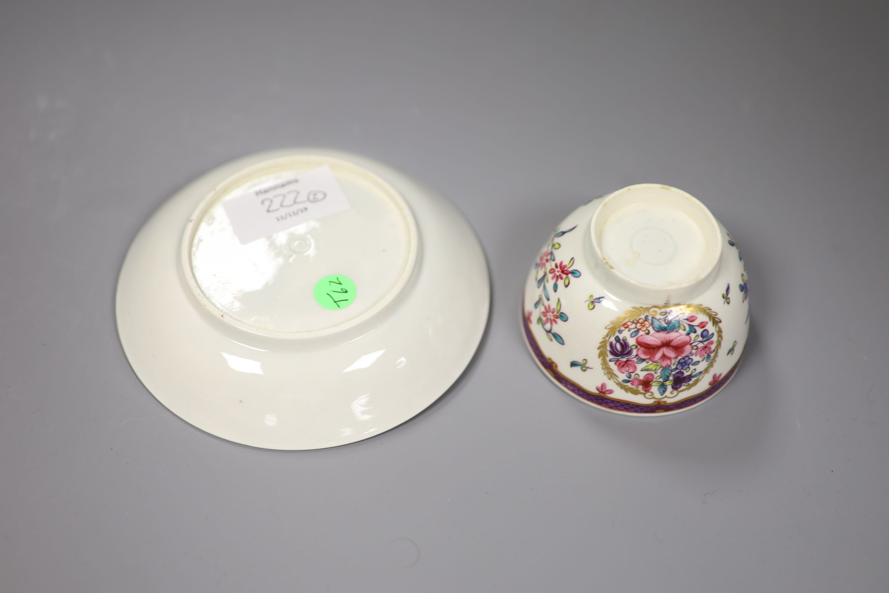 An 18th century Worcester teabowl and saucer painted Companie des Indes style with flowers in a circular gilt leaf panel